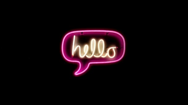 Neon sign of a speech bubble around the word "hello"
