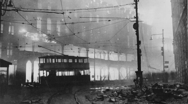 Old photograph of a Sheffield street after the blitz - buildings on fire and burned out tram